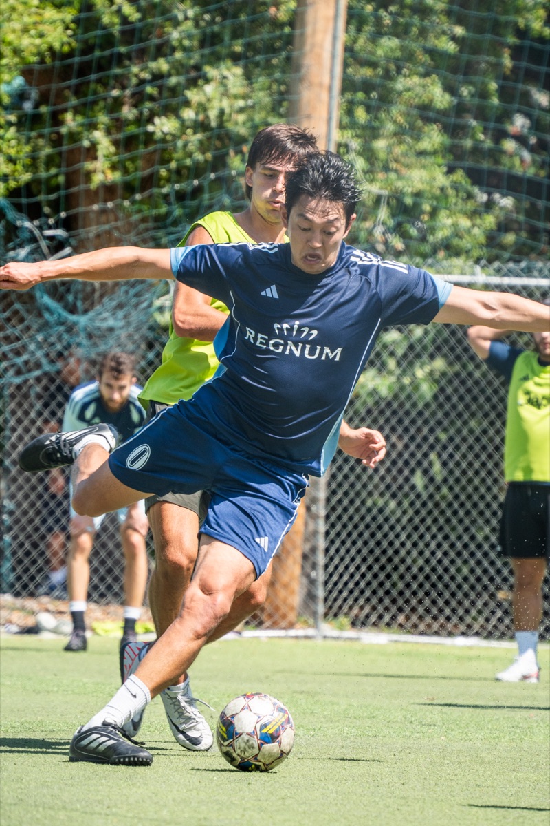 Player striking the ball while shielding off a defender in the Orange Cup