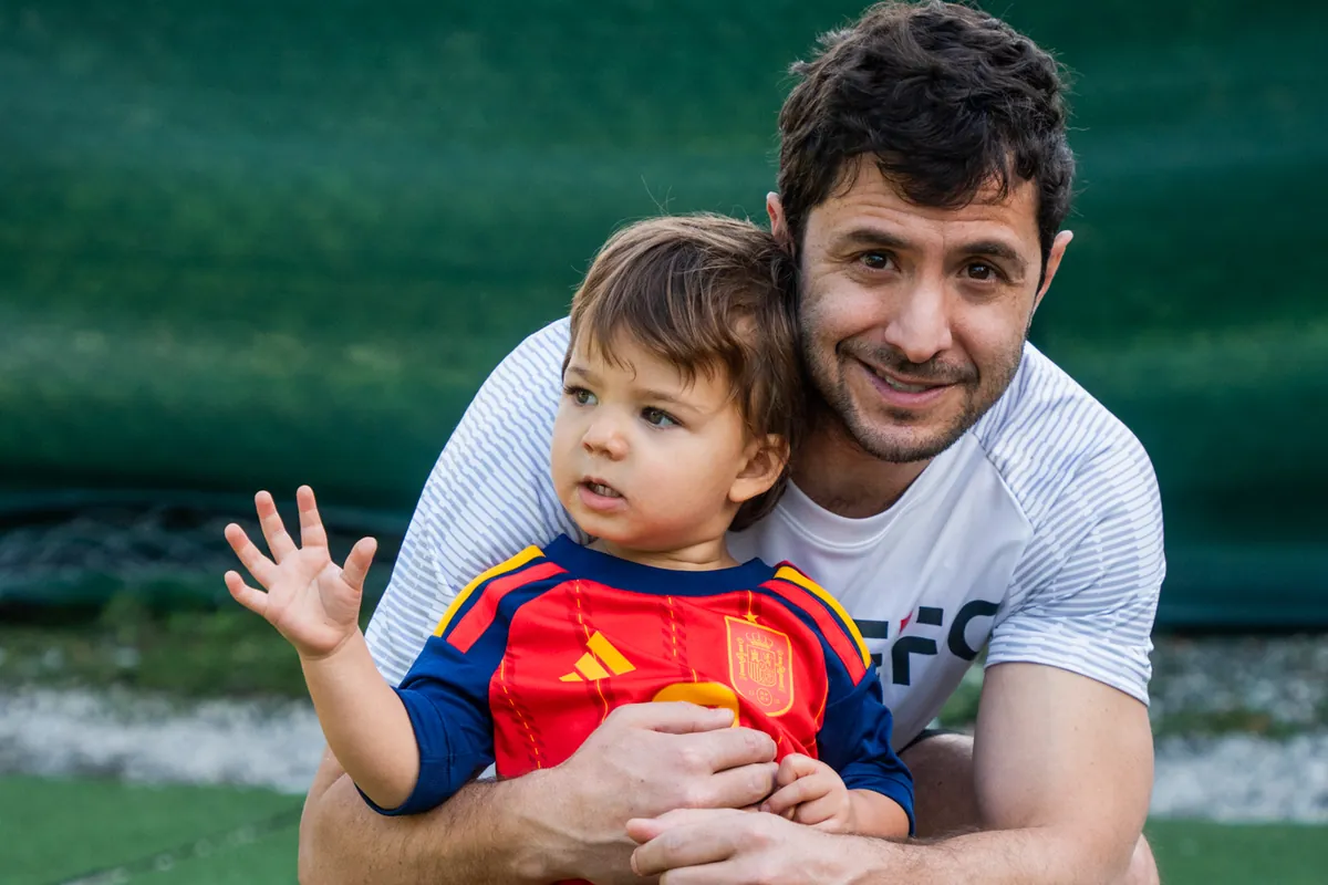 A CFL player holding his son in a Spain kit at the Family Fest match day in Miami