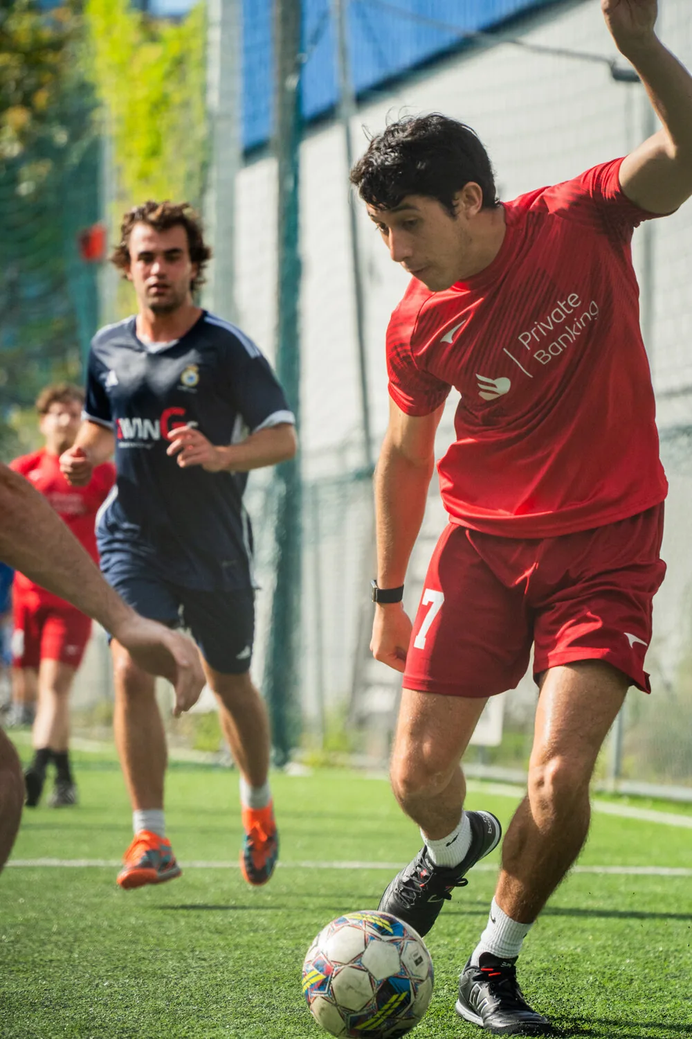 Captain in Private Banking kit, mid-action with the ball